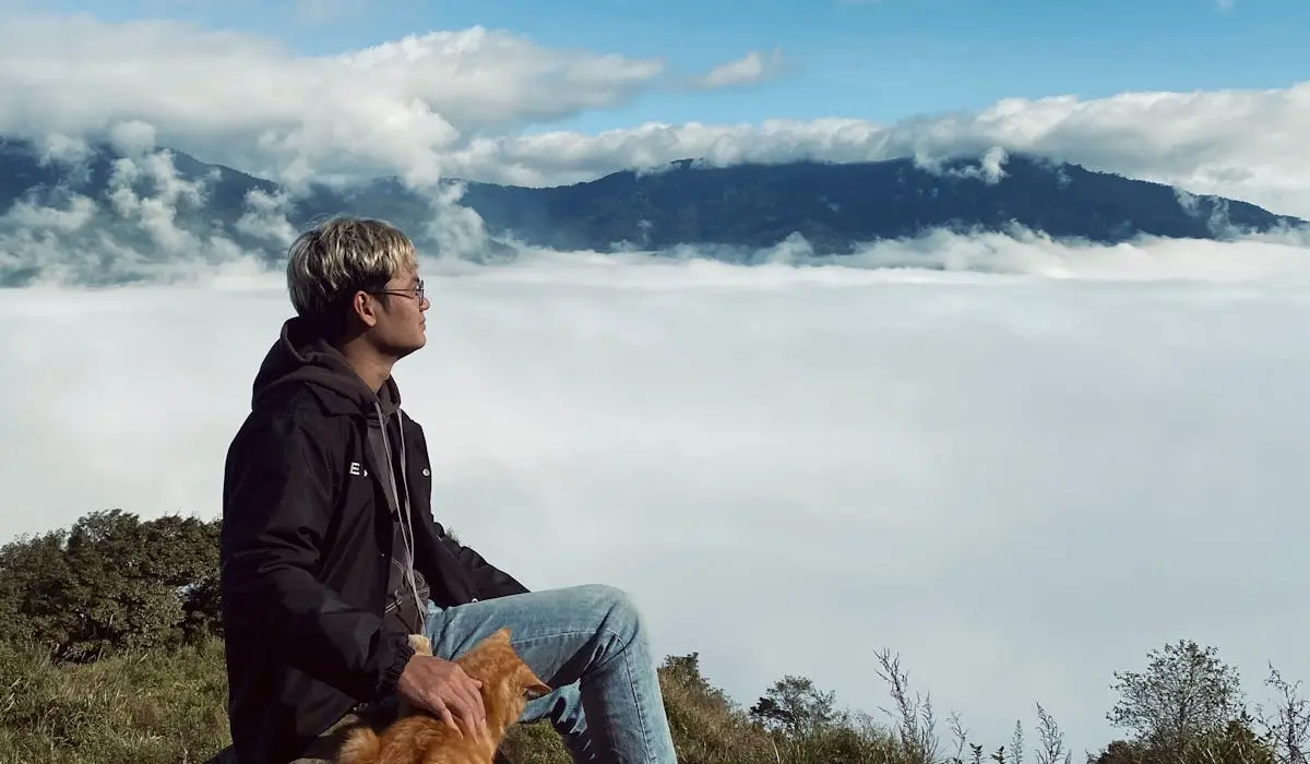 cat and owner sitting in top of mountain